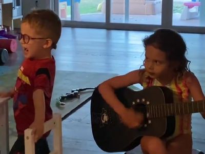 Lily-Rose River Pardo is playing a guitar as the son is singing.